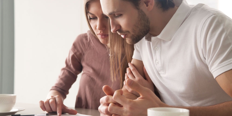 A man and woman looked concerned at paperwork as they sit at a table