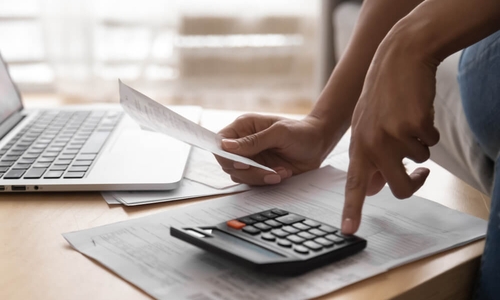 African woman holding paper bills using calculator, close up vie (1).jpg