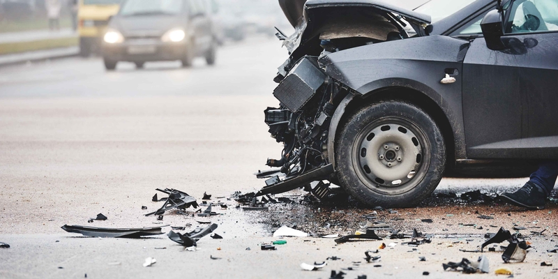A black car with front-end damage after a collision
