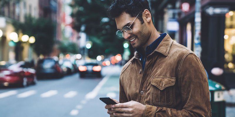 Millennial man calls an uber from his phone on downtown street