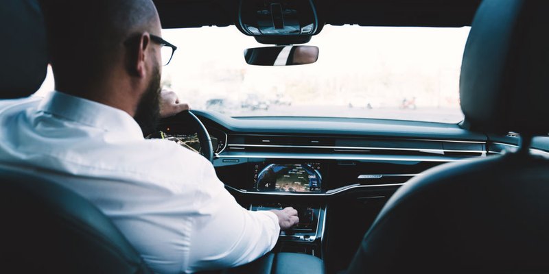 A man reaches for the volume dial while driving his car