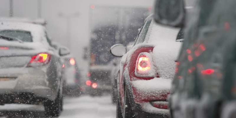 Vehicles move slowly in a traffic jam during a snow storm