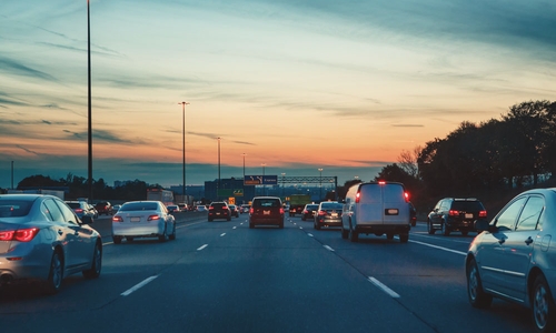 Several lanes of traffic on a highway during dusk