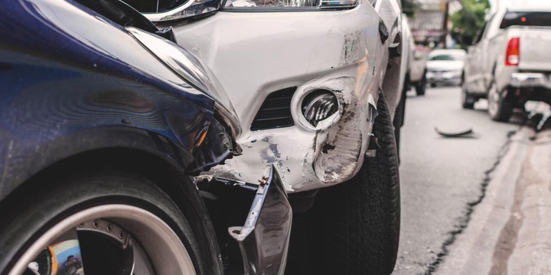 A close up image of a collision between a blue vehicle and white vehicle