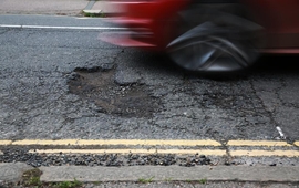 red car driving over a pothole.jpg
