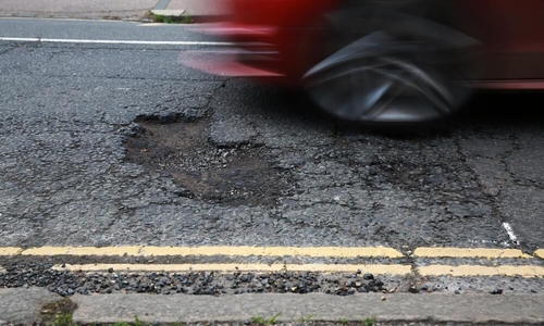 red car driving over a pothole.jpg