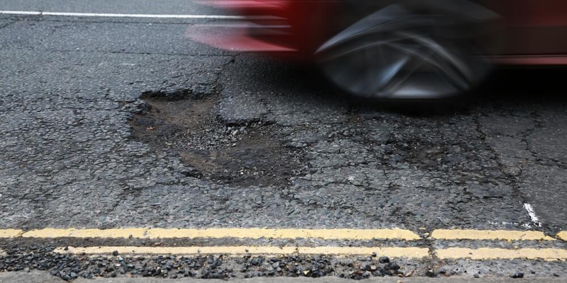 red car driving over a pothole.jpg