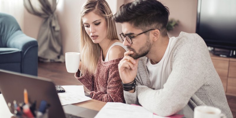A young couple review their finances with paperwork and a laptop